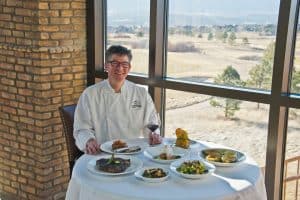 Chef at the Steakhouse at Flying Horse with prepared dishes
